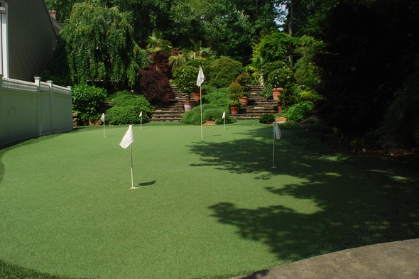 Tucson Synthetic grass golf green with flags in a landscaped backyard